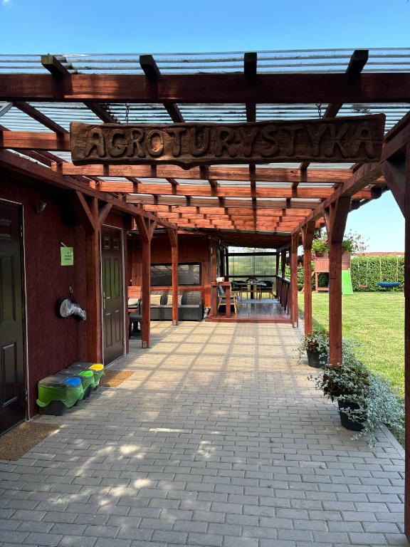 Klimatyczne wejście z drewnianym szyldem „Agroturystyka" i zadaszonym patio