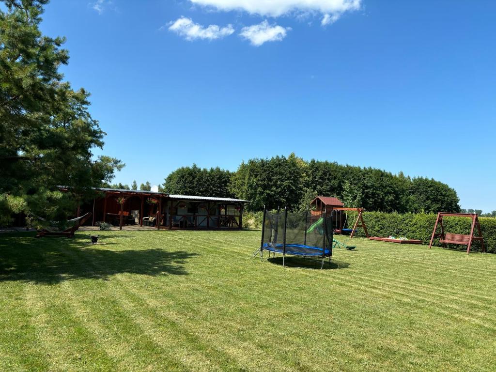 Panorama dużego, zielonego ogrodu z placem zabaw, trampoliną i huśtawkami